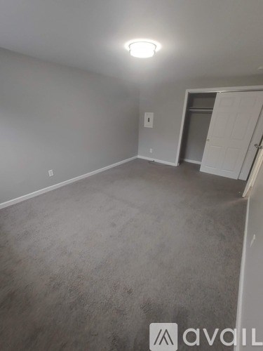 A room with a carpeted floor and a door on the right side.