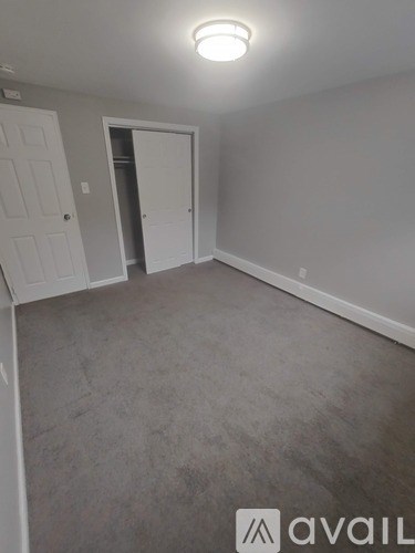 A room with a carpeted floor and two doors.