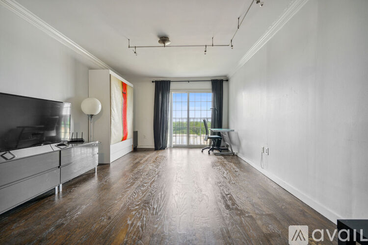 A spacious living room with wood flooring and a television.
