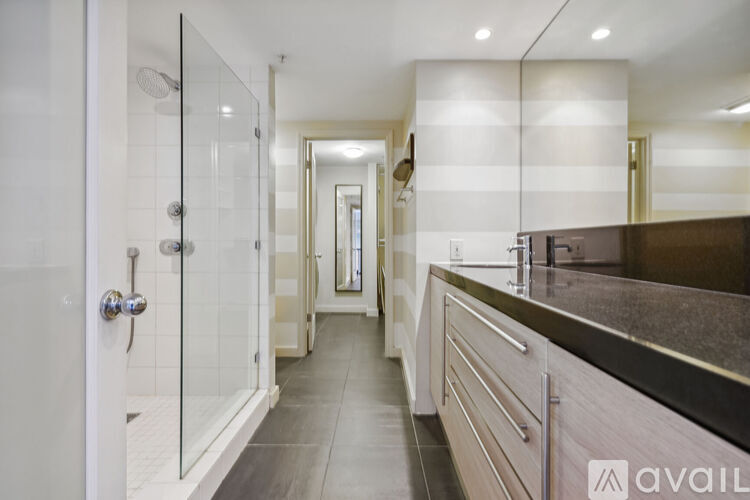 A modern bathroom with a walk-in shower and a long counter.