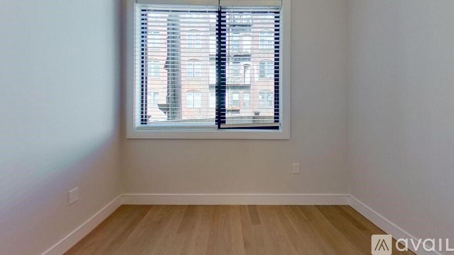 A room with a window showing a view of a building outside.