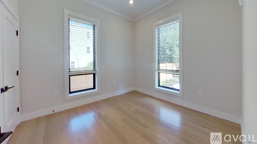 A room with wooden floors and two windows.