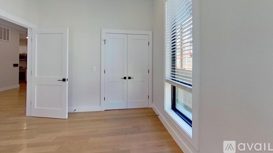 A room with a white door and a window with blinds.