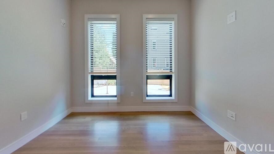A room with two windows and wooden floors.