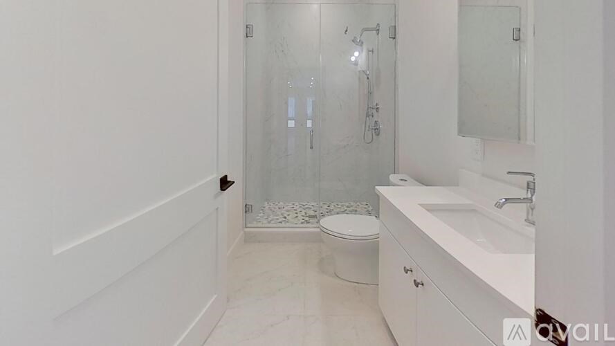 A white bathroom with a toilet, sink, and shower.
