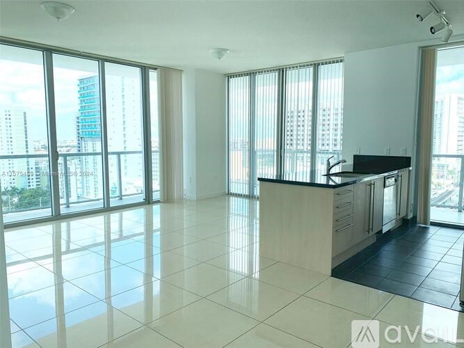 A spacious, well-lit room with large windows and a kitchen area.