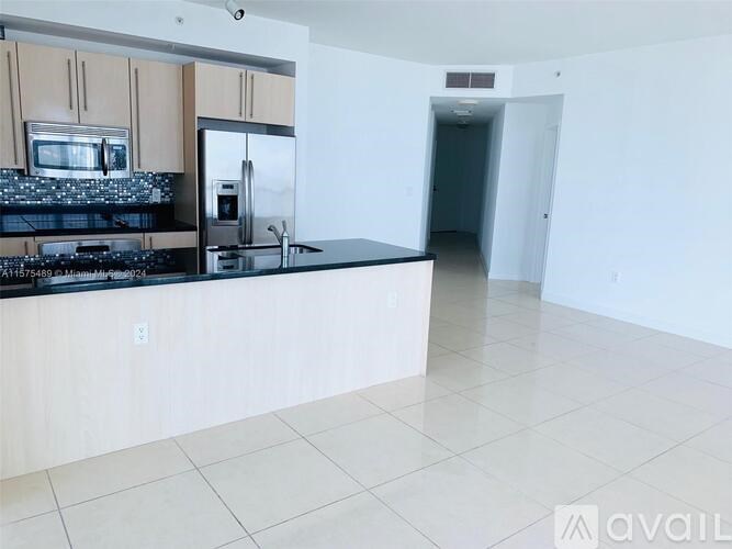 A kitchen with a black countertop and stainless steel appliances.