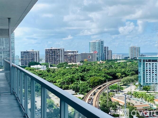 A cityscape with a mix of modern and older buildings, a highway, and greenery.