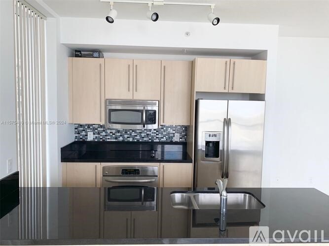 A kitchen with a black countertop and stainless steel appliances.