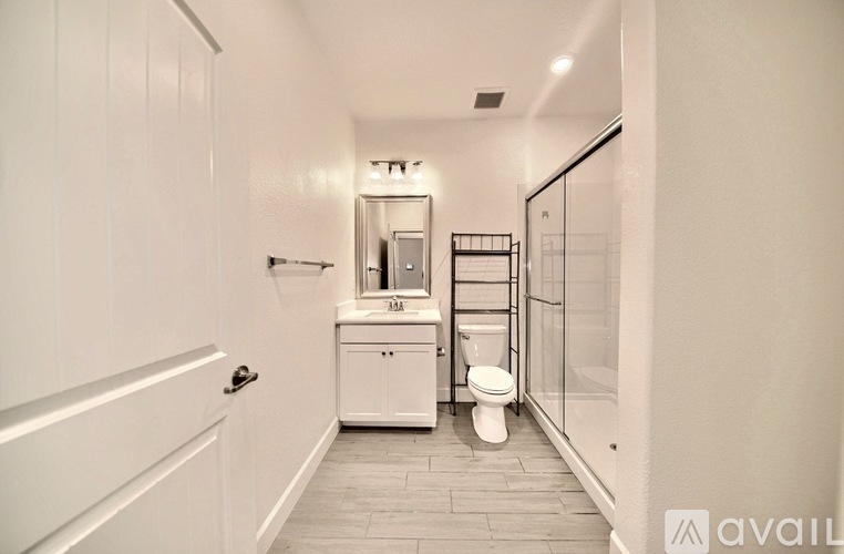 A white bathroom with a toilet, sink, and mirror.