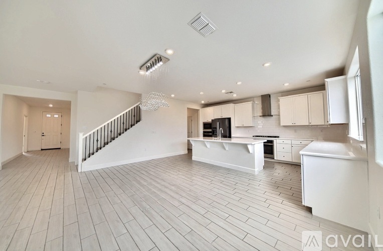 A spacious kitchen with white cabinets and a staircase.