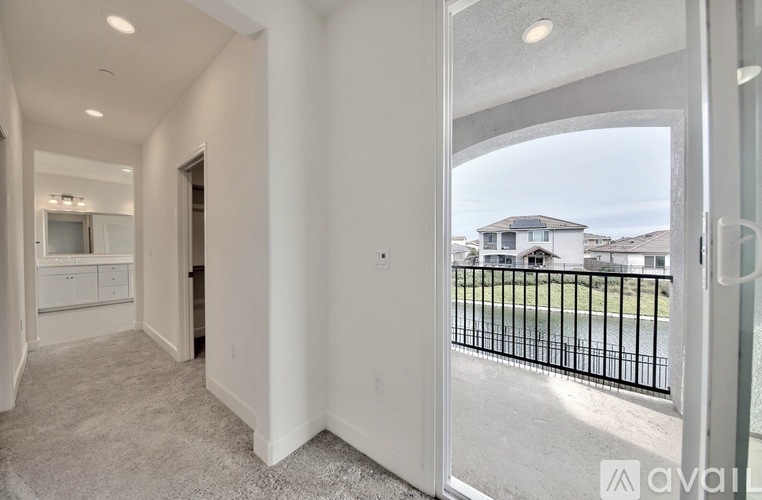 A spacious, empty room with a view of a house through a glass door.