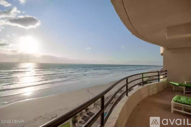 A balcony overlooks a beach with the sun shining brightly in the sky.