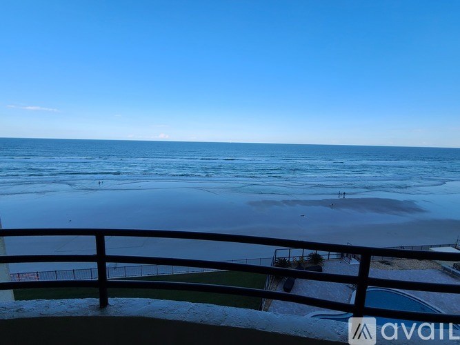 A beach scene with a railing in the foreground and the ocean in the background.