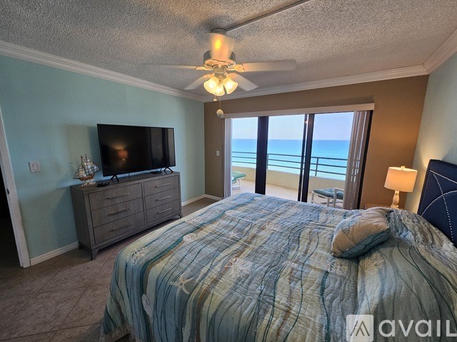 A bedroom with a large bed, a flat screen TV, and a view of the ocean.