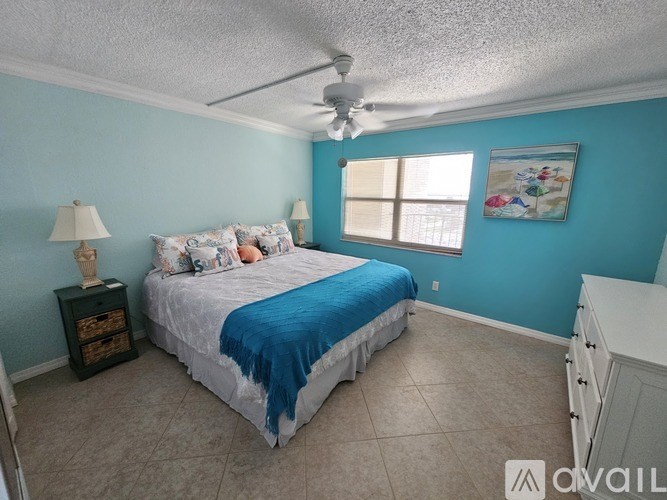 A bedroom with a bed, a ceiling fan, and a nightstand with a lamp.