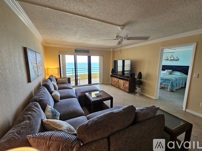 A living room with a large couch and a view of the beach.