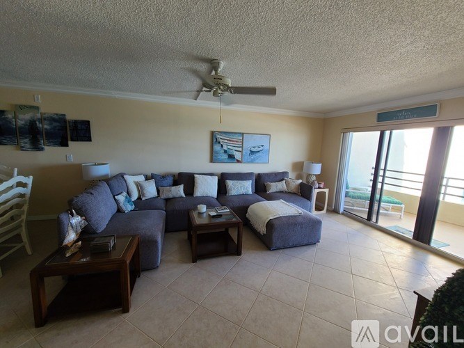 A living room with a grey couch and a ceiling fan.