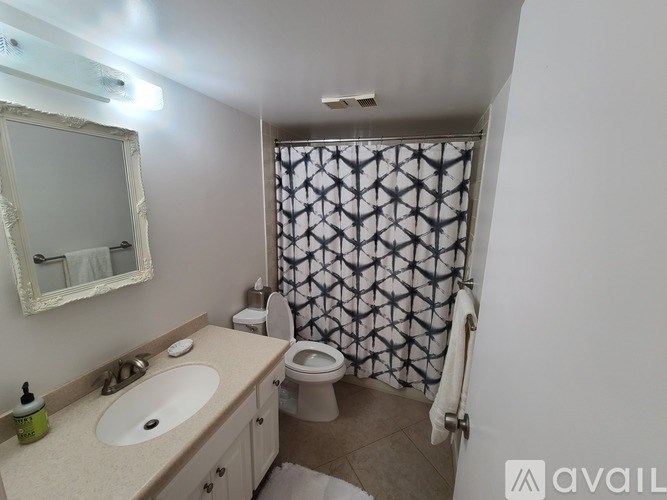 A bathroom with a toilet, sink, and shower curtain.