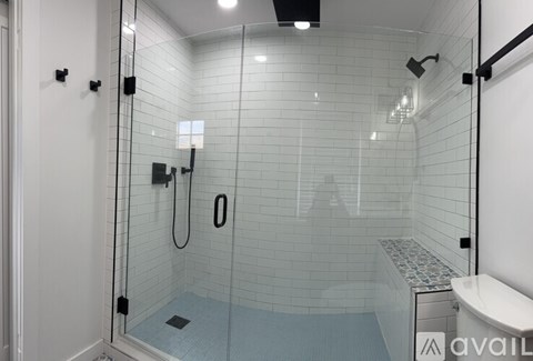 A bathroom with a glass shower stall and a white toilet.