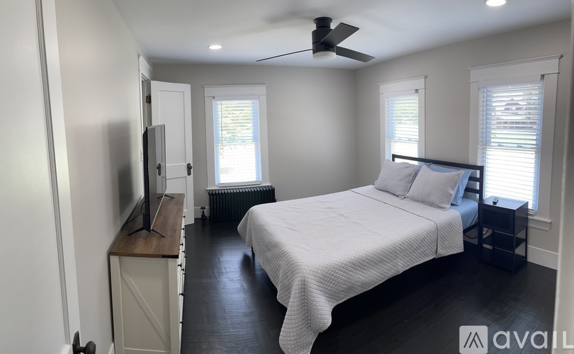 A bedroom with a bed, dresser, and television.