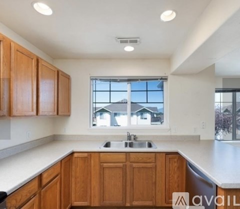 A kitchen with wooden cabinets and a window overlooking a house.