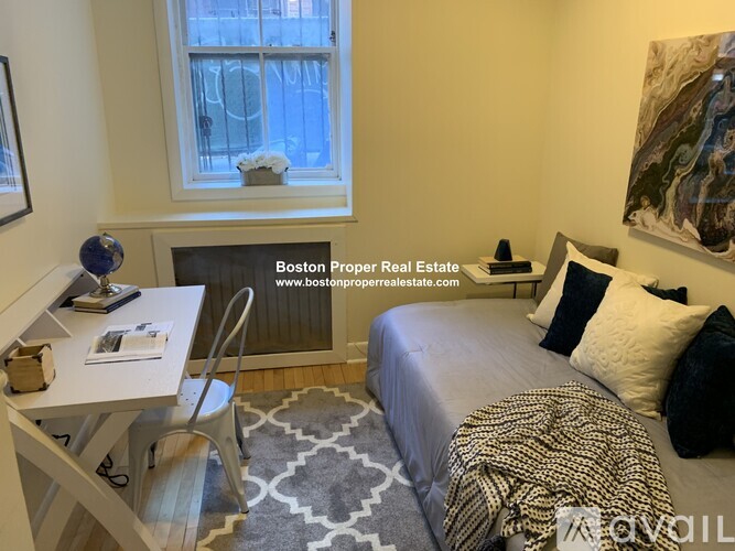 A bedroom with a bed, desk, and window.