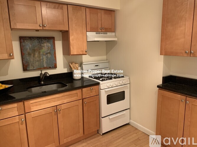 A kitchen with wooden cabinets and a white stove top oven.