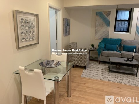A modern living room with a glass dining table and white chairs.