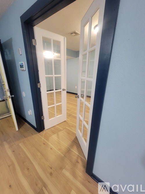 A room with a white door and a wooden floor.