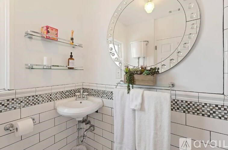 A bathroom with a white sink and a round mirror.