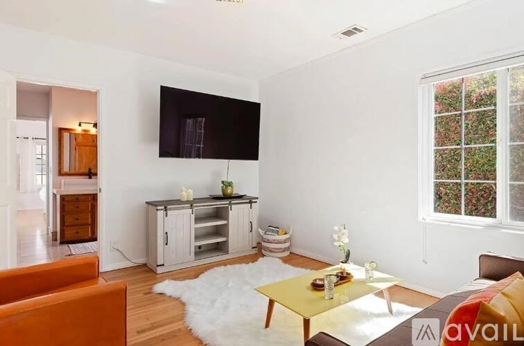 A living room with a white rug and a yellow coffee table.