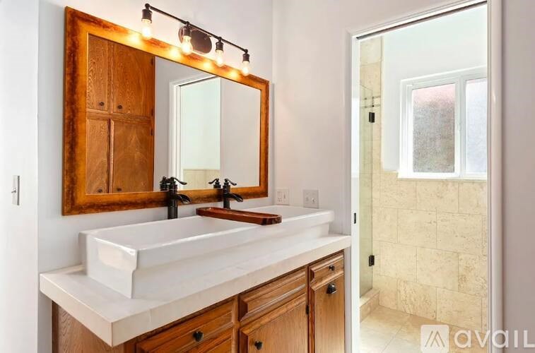 A bathroom with a white sink and a mirror with lights above it.