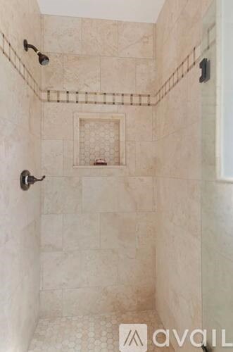 A bathroom with a tiled shower and a glass door.