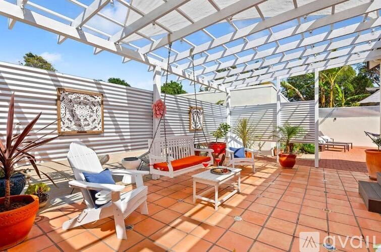 A patio with white furniture and a white pergola.
