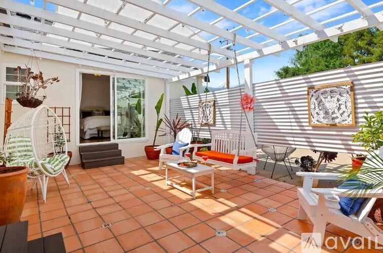 A patio with a white pergola and a table with chairs.