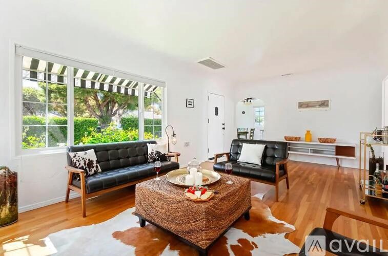 A living room with a black couch and a brown woven coffee table.