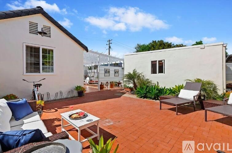 A patio with a table and chairs is surrounded by two houses.