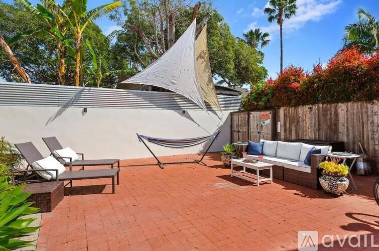 A patio with a hammock and a bench.