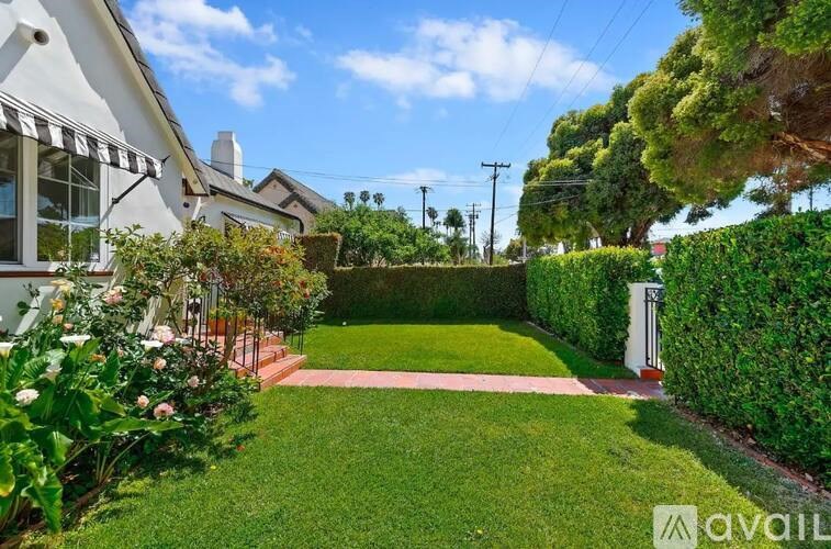 A well-maintained garden with a white house in the background.