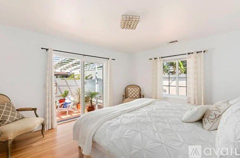 A bedroom with a large bed and a chair by the window.