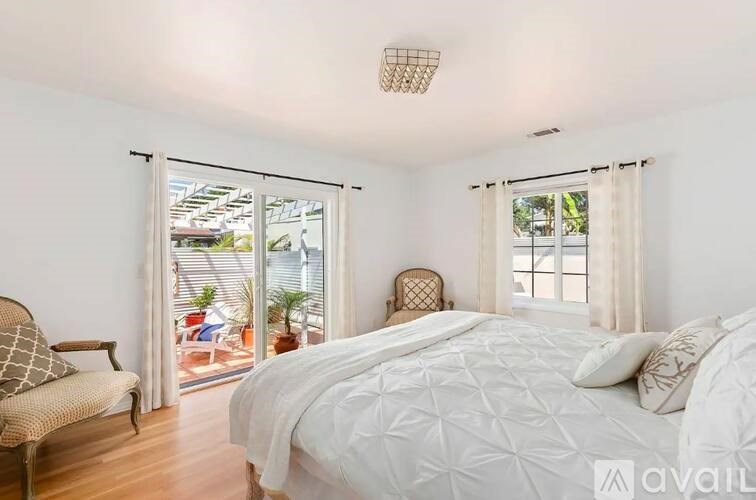 A bedroom with a large bed and a chair by the window.