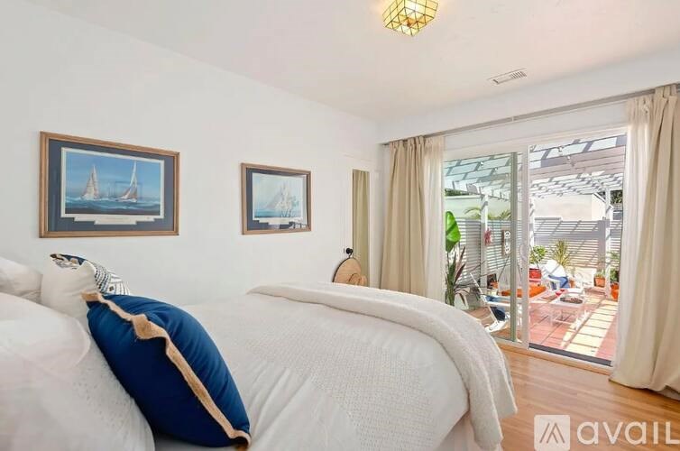 A bedroom with two beds and a balcony overlooking a patio.