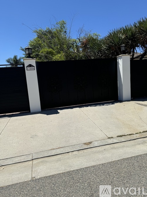 A black fence with two white posts and a sign that reads "12800" is in the foreground.