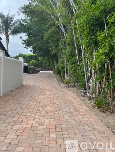 A long brick walkway with black trash cans on the side.