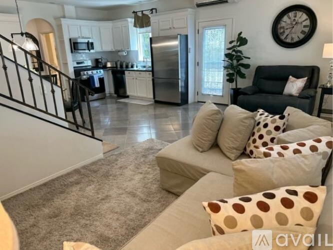 A living room with a couch, pillows, and a clock on the wall.