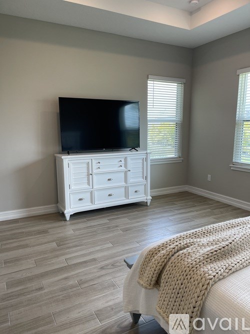 A bedroom with a bed covered in a blanket and a television on a cabinet.