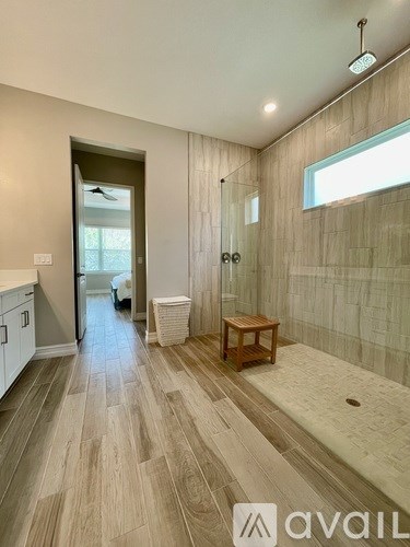 A bathroom with a wooden floor and a glass shower stall.