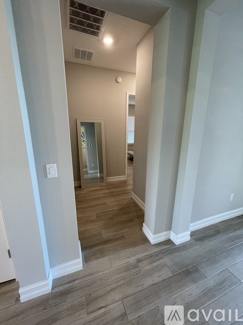 A hallway with a door at the end and a light on the wall.