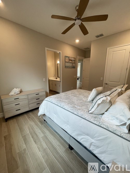 A bedroom with a bed, dresser, and ceiling fan.